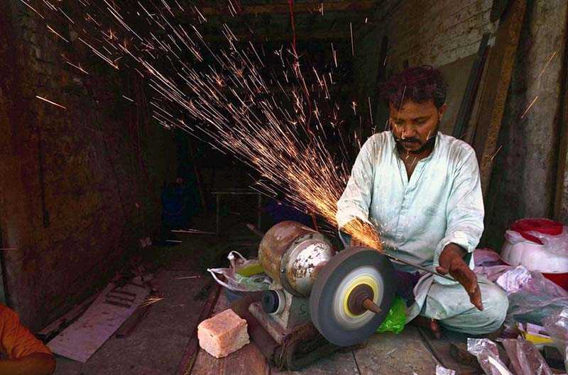 Worker Sharpens Knives for Sacrificial Animals Ahead of Eid-ul-Azha at Fort Road